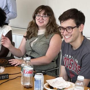2 pre-doc research assistant smile during a presentation