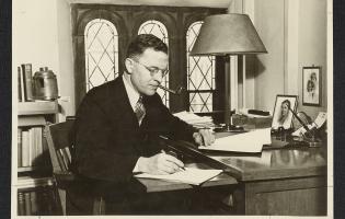 Photo of J. Douglas Brown working at his desk. Photo taken in 1938.